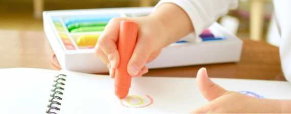 クレヨンで絵を描く子供の手元