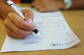 アンケート用紙に記入する手元