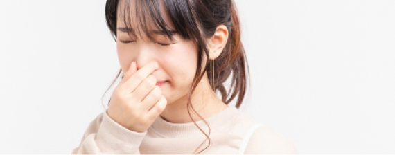 鼻をつまんで顔をしかめている女性